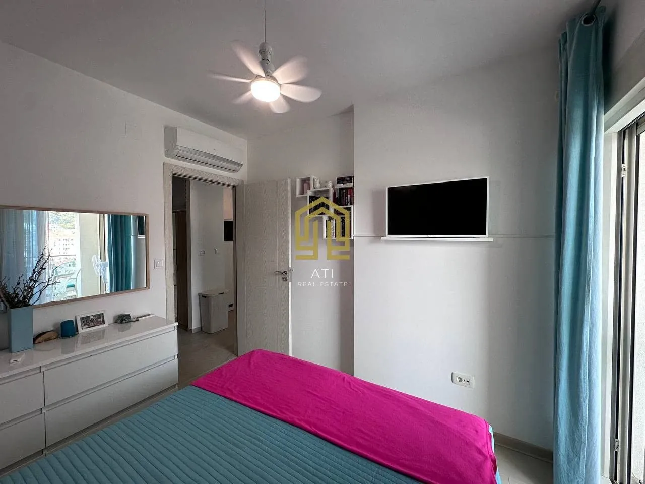 Furnished bedroom with a double bed and wall-mounted TV.