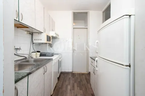 Smaller kitchen with white cabinetry, sink, and refrigerator. - image 7