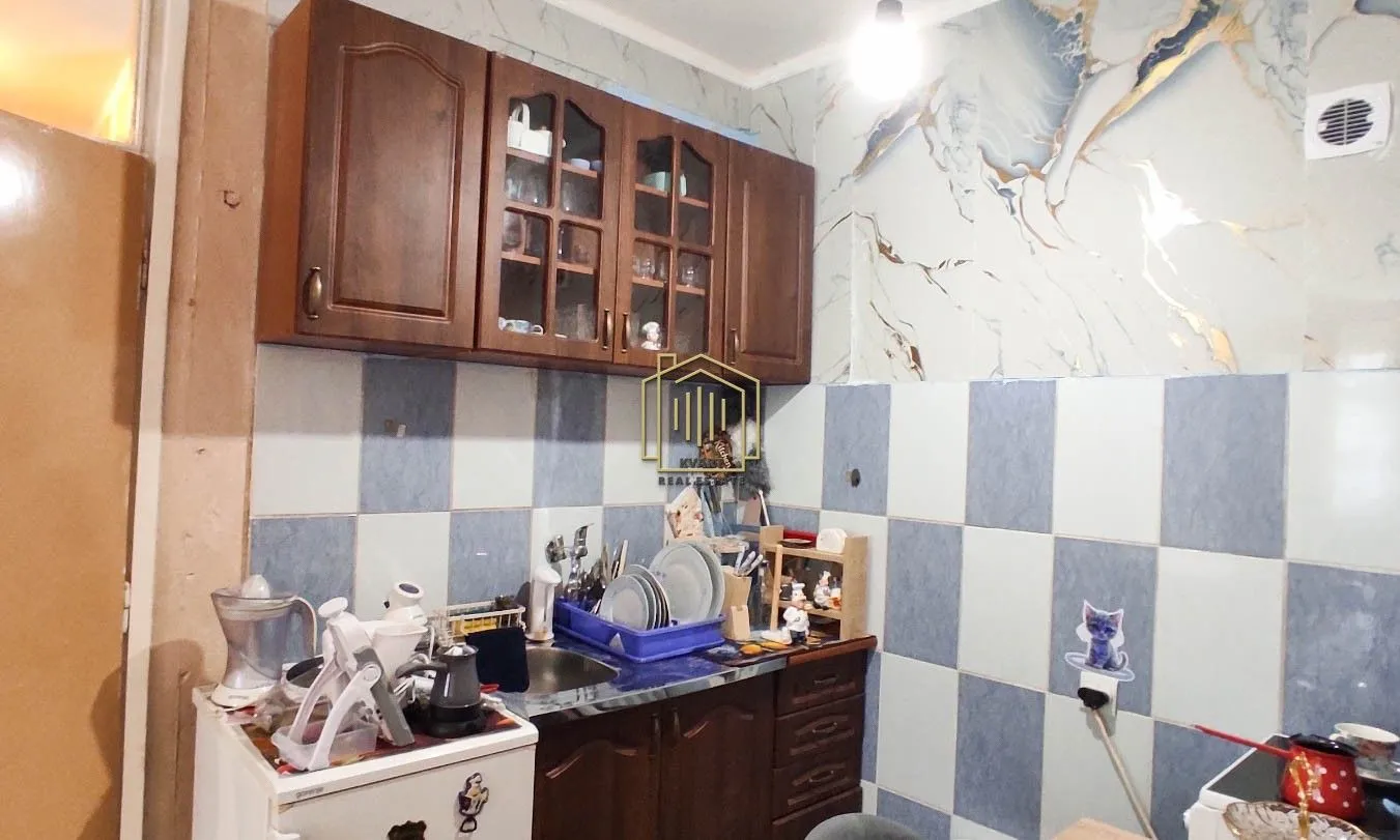 Kitchen with wooden cabinetry and wall tiles.