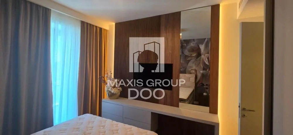 Modern bedroom with a double bed, wood wall paneling, and a window with curtains.