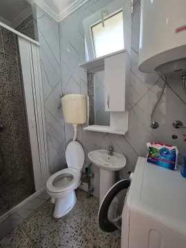 Bathroom equipped with a toilet, sink, shower cabin, and washing machine. - image 17