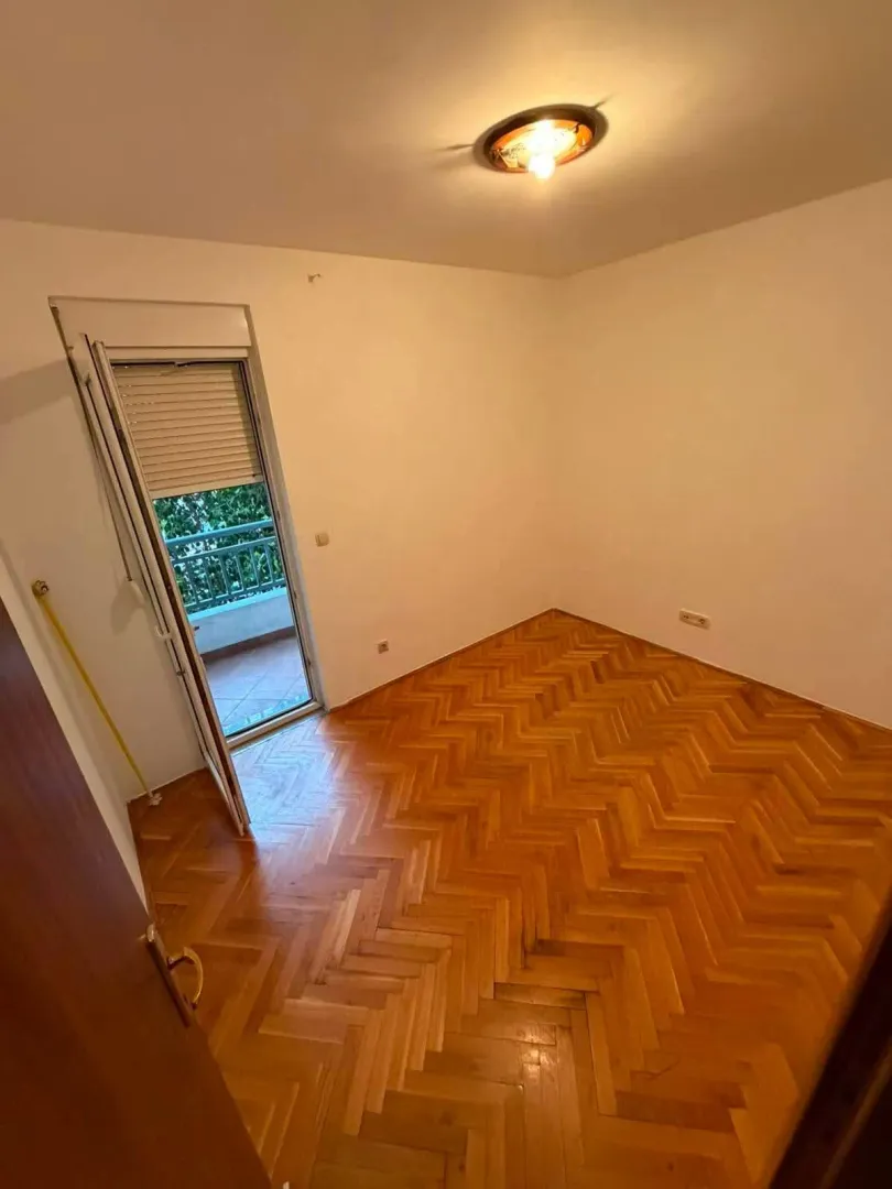 Prazna soba sa parketom i izlazom na terasu.