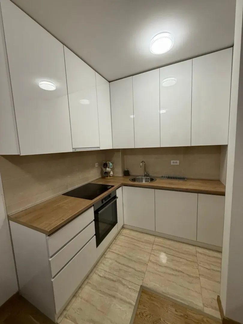 Modern kitchen with white cabinets and a wooden countertop.