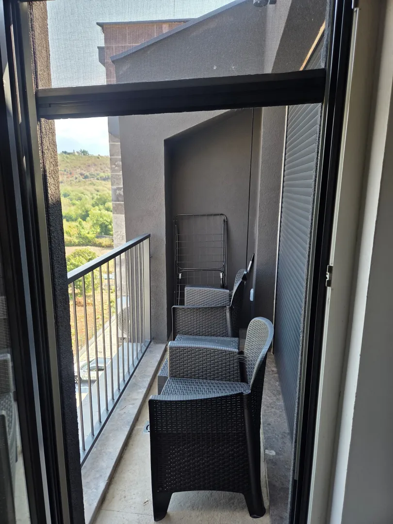 Manji zatvoreni balkon sa garniturom za sjedenje i pogledom na prirodu.