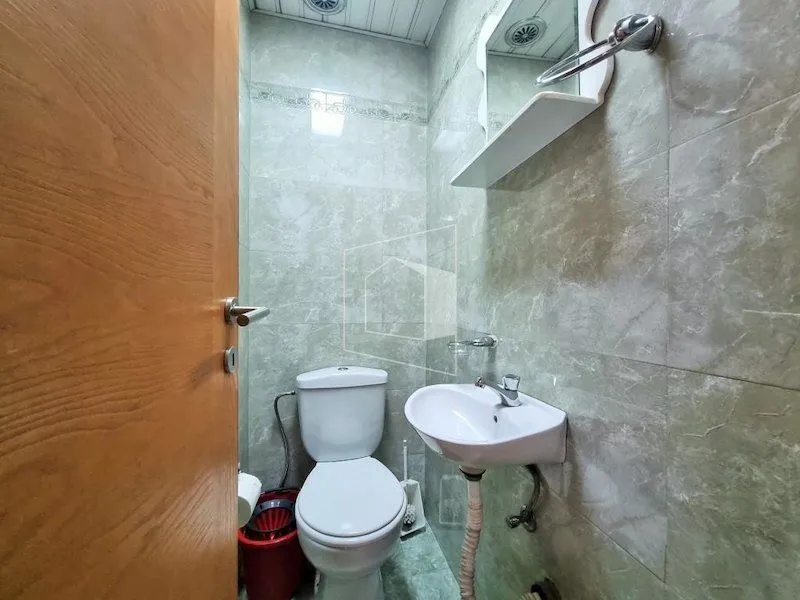 Manje kupatilo sa WC šoljom, umivaonikom i ogledalom.