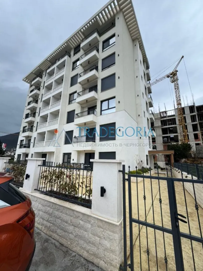 Pogled na spoljašnjost moderne stambene zgrade sa terasama i dvorištem.