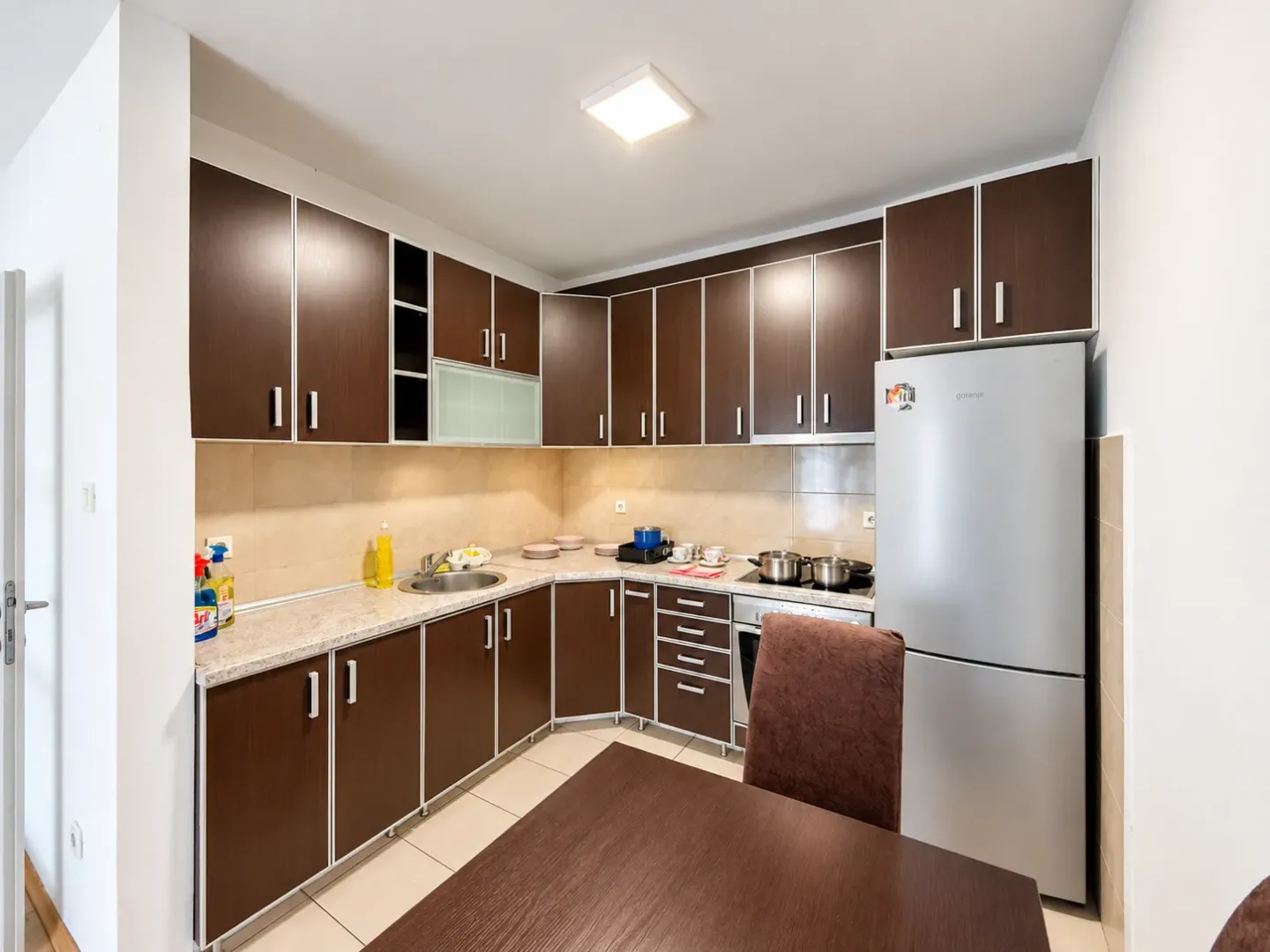 Kitchen with dark wooden units and a built-in refrigerator.