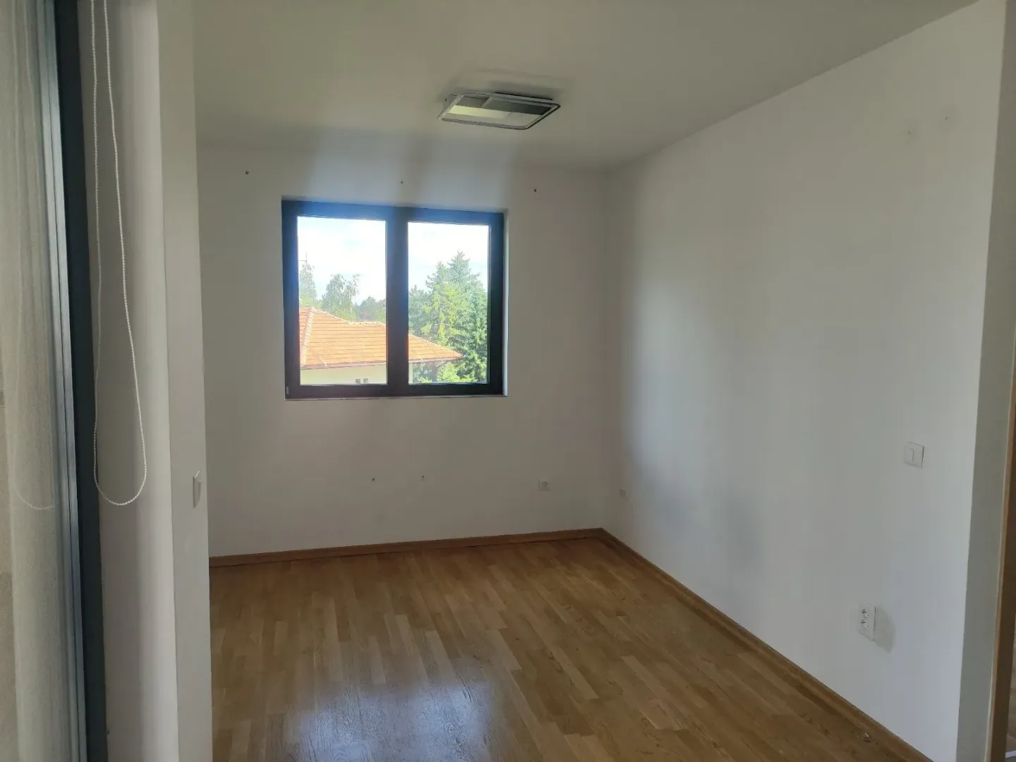 Prazna soba sa parketom i prozorom.