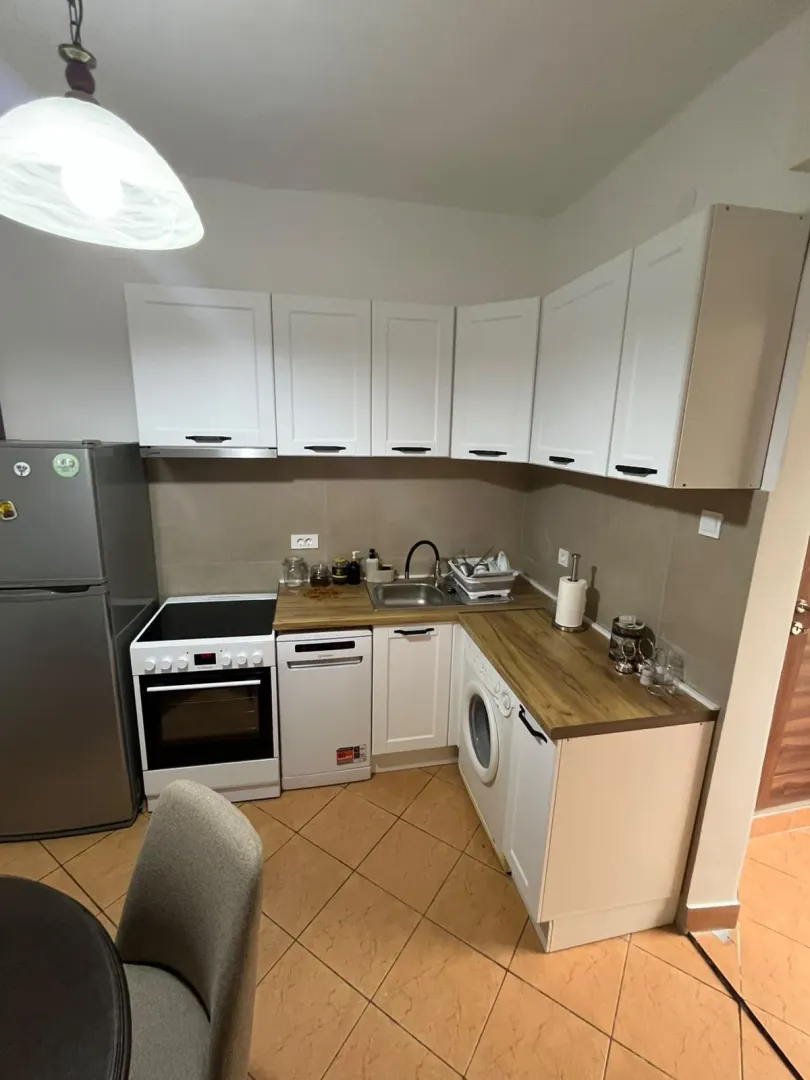 Compact kitchen with white cabinetry, a stove, a refrigerator, and an integrated washing machine.