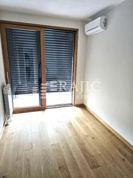Empty room with wooden flooring, air conditioning unit, and large glass doors. - image 10