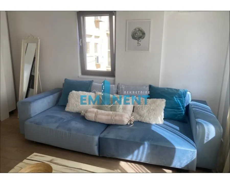 Living room with a comfortable blue sofa and a window.