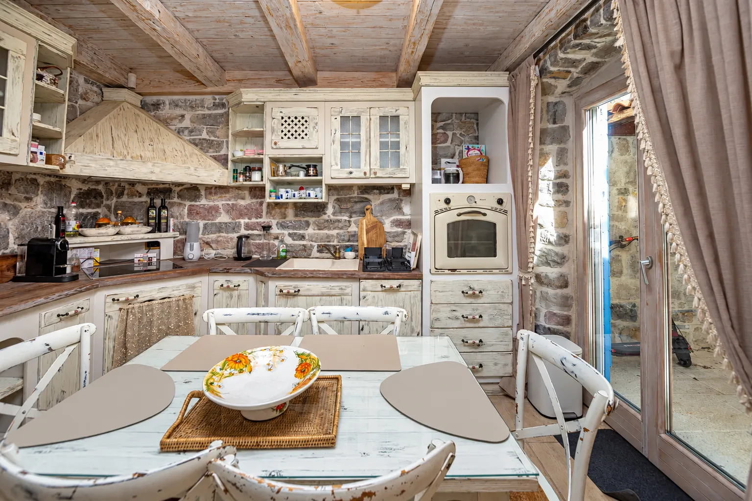 Rustic kitchen with wooden elements, stone walls, and a dining table.