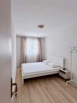 Bright bedroom with a white bed and parquet flooring. - image 4