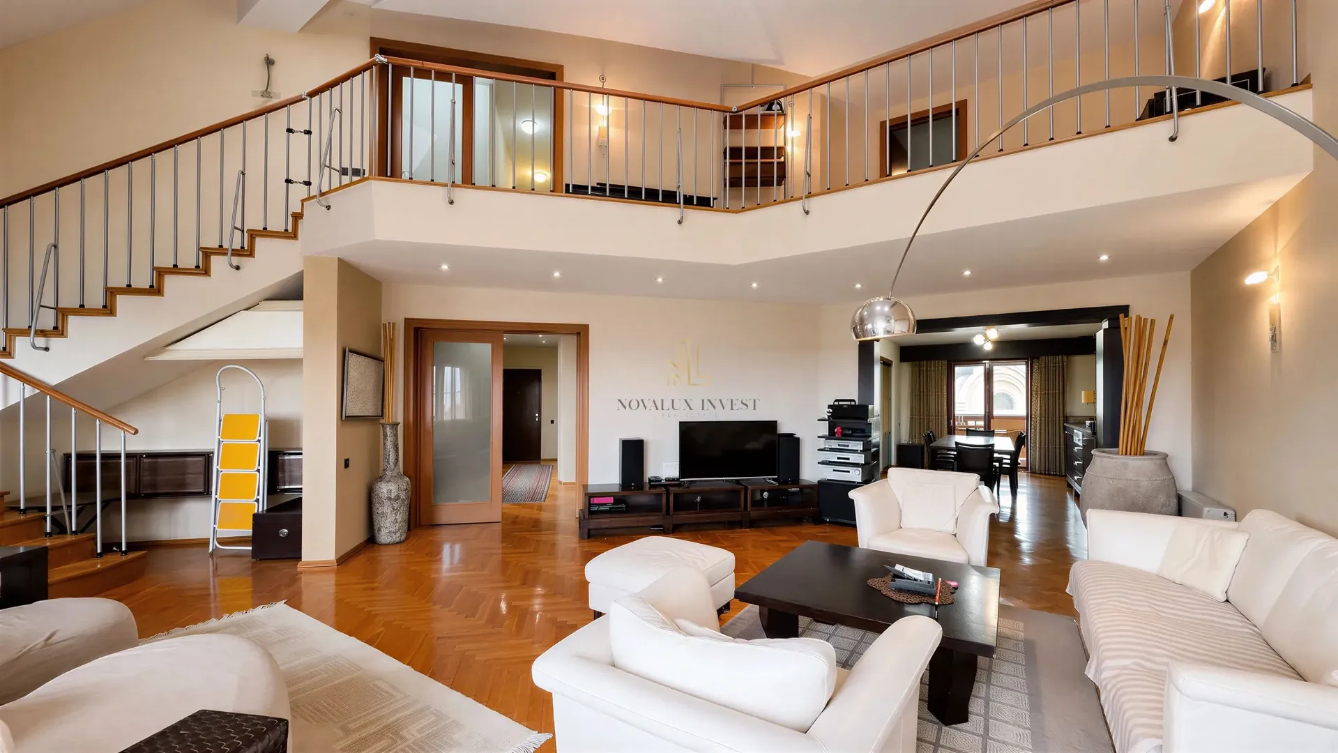 Spacious living room with seating area, staircase, and upper-level gallery.