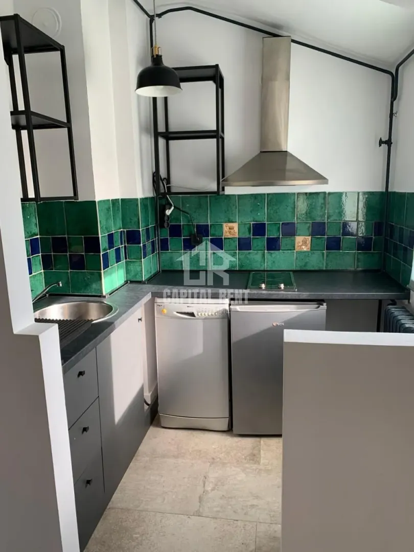 Small kitchen with dark cabinets and colorful ceramic tiles on the wall.