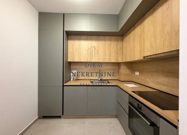 Moderna kuhinja sa sivim elementima i drvenim detaljima.
