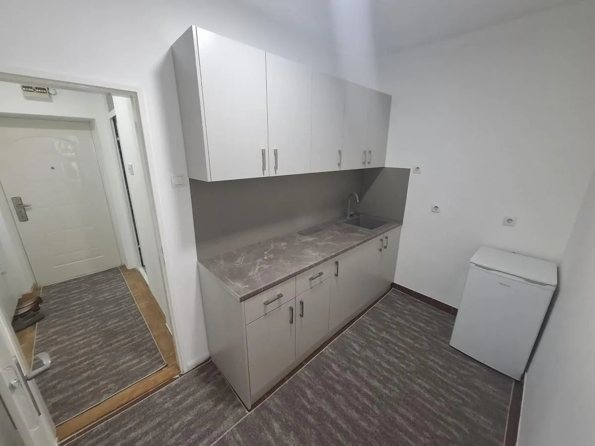 Small kitchen with light-colored cabinets and a small refrigerator.
