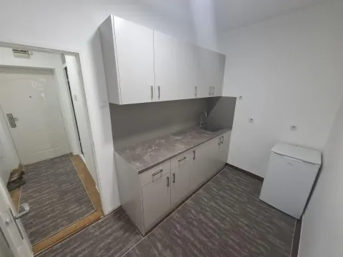 Small kitchen with light-colored cabinets and a small refrigerator. - image 3