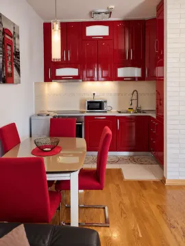 Modern kitchen with glossy red cabinetry and a dining table. - image 6