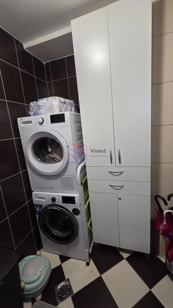Kupatilo sa mašinom za veš i bijelim ormarićem.