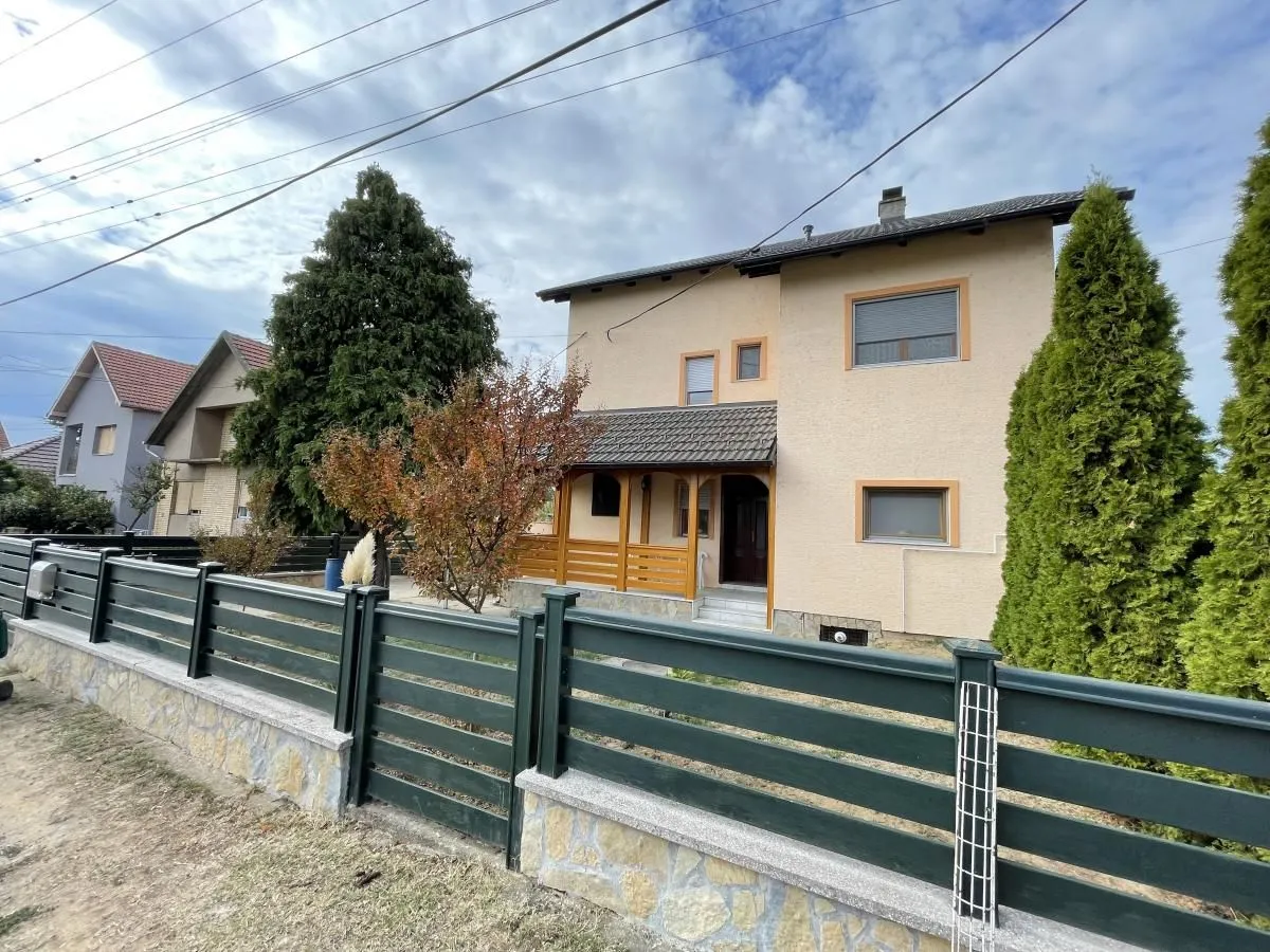 Pogled na dvorište i prednju fasadu kuće sa ogradom.