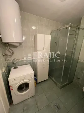 Bathroom with a shower cabin, cabinet, water heater, and washing machine. - image 11
