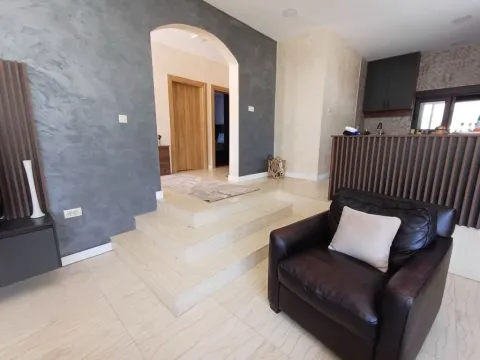 Living room with armchairs and steps leading to the hallway and kitchen. - image 4