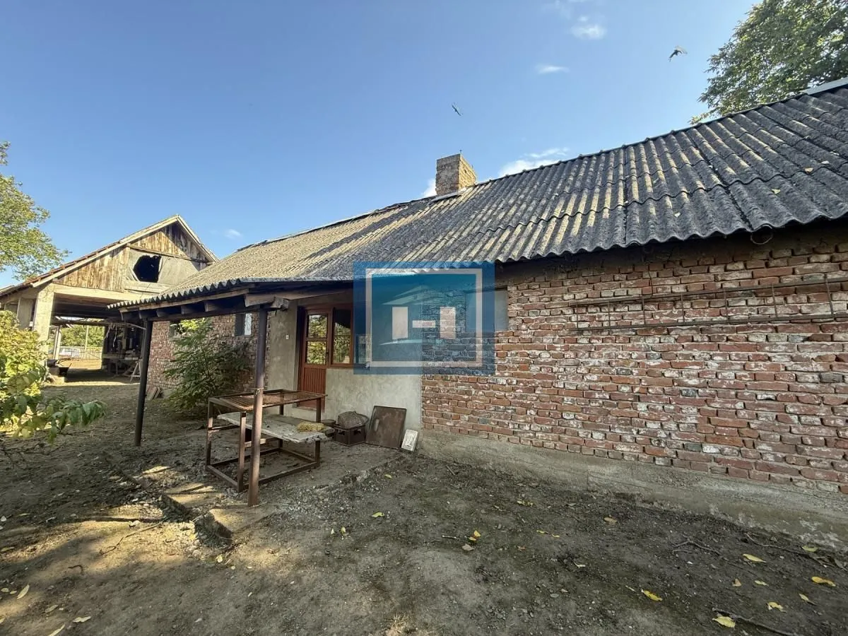 Pogled na dvorište i stariju kuću sa ciglenom fasadom.