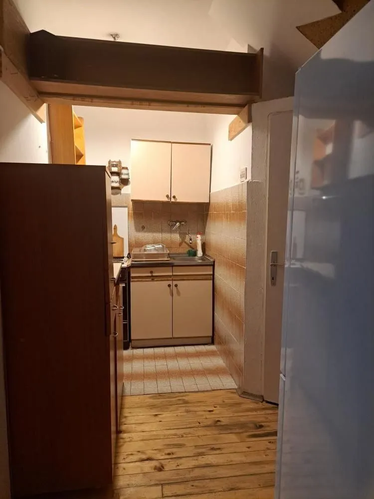 Small kitchen with a sink, cabinets, and wooden flooring.