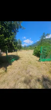 Ograđeno dvorište sa zelenom kapijom i pogledom na prirodu i planine. - image 7