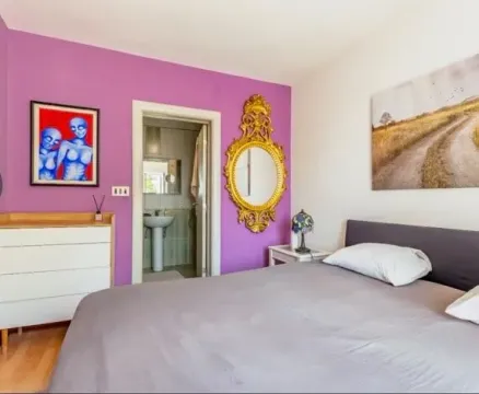 Furnished bedroom with a double bed and a purple accent wall. - image 5
