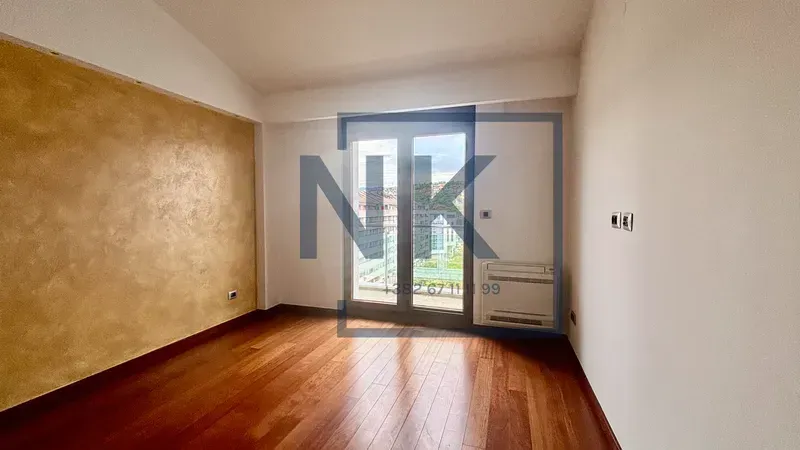 Empty room with wooden flooring and balcony doors.