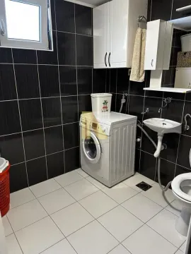 Manje kupatilo sa tamnim zidnim pločicama, veš mašinom i sanitarijama. - image 26