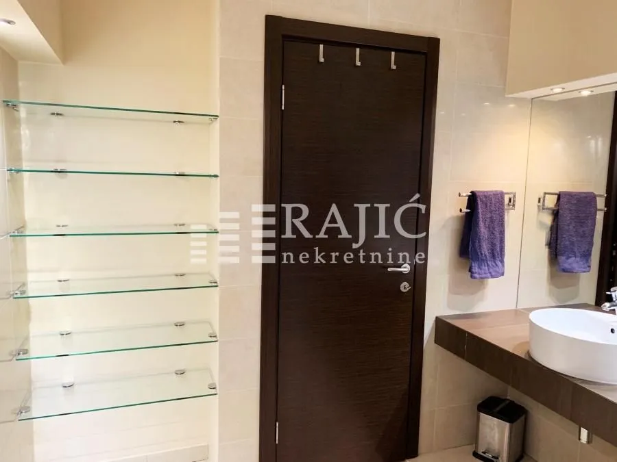 Modern bathroom with a washbasin and glass shelves.