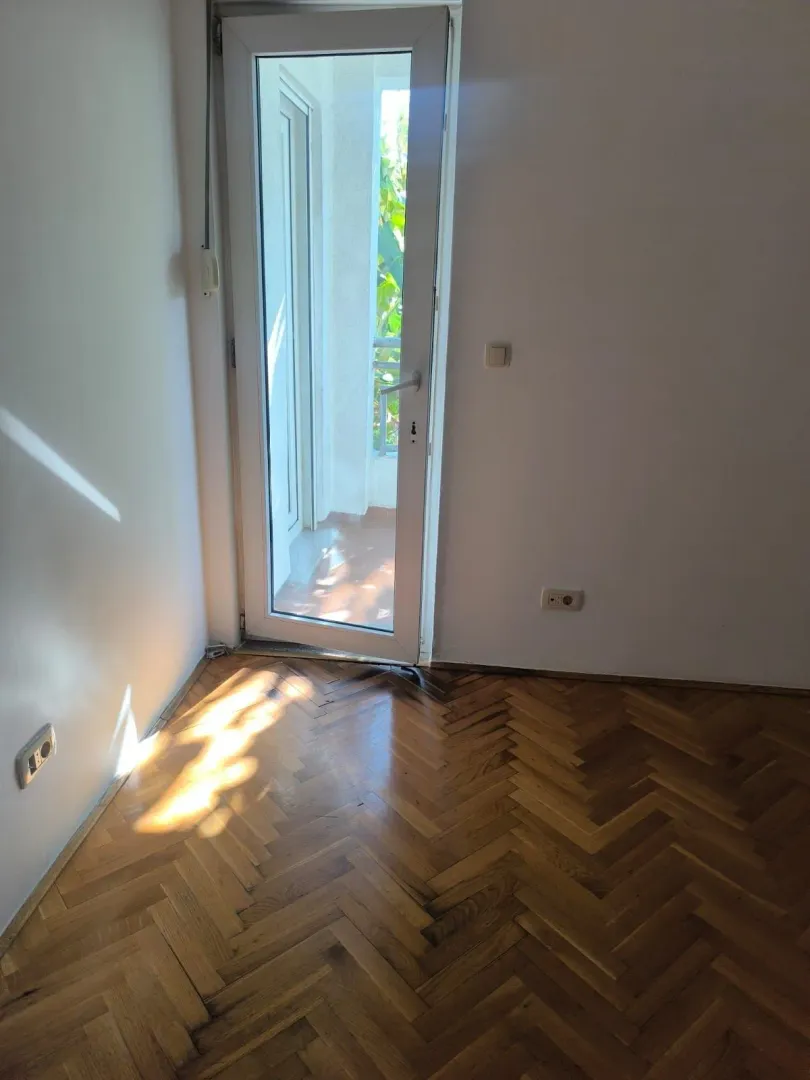 Prazna soba sa parketom i izlazom na terasu.