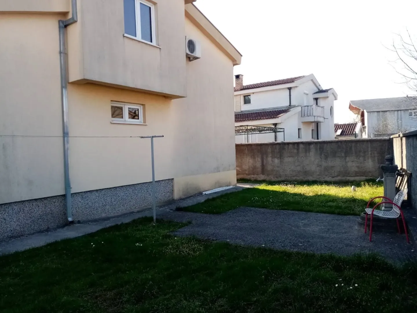A backyard of a house with a lawn and a paved area.