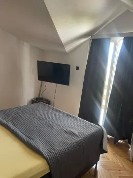 Spavaća soba sa bračnim krevetom, televizorom na zidu i izlazom na terasu. - image 2