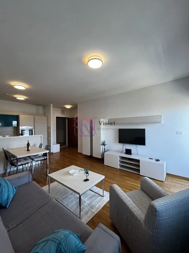Spacious living room with a sofa, TV, and a dining area connected to the kitchen.