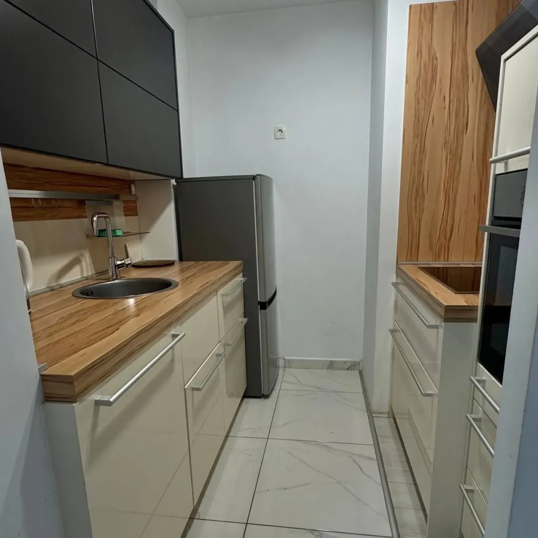 Small modern kitchen furnished with wood-accented and dark-toned cabinetry.