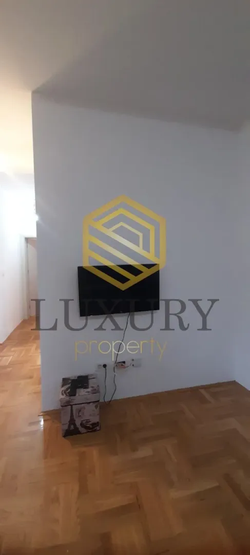 Living room with parquet flooring and a wall-mounted TV.
