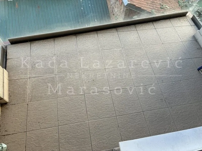 Top-down view of a tiled balcony with a glass railing.