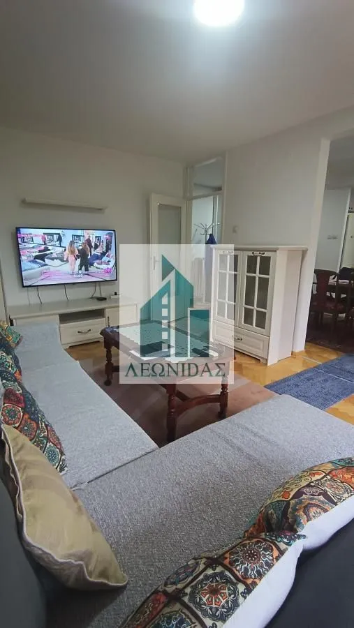 Living room with a sofa set, television, and chest of drawers.