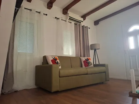 Living room with a green sofa and wooden ceiling beams. - image 15
