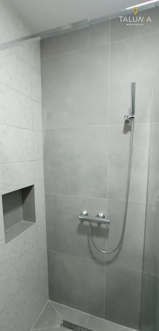 Modern shower cabin with grey tiles and a built-in niche.