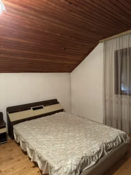 Jednostavna spavaća soba sa kosim drvenim plafonom i bračnim krevetom. - image 10