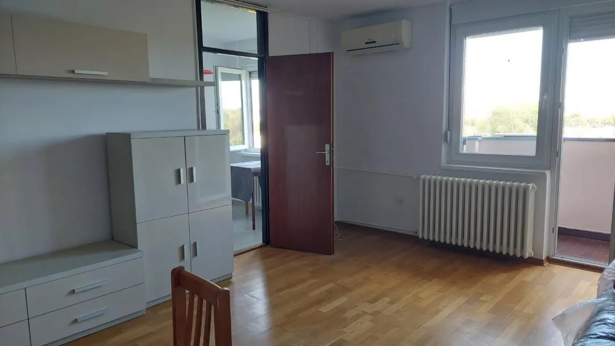 Dnevna soba sa drvenim podom, nameštajem i izlazom na terasu.