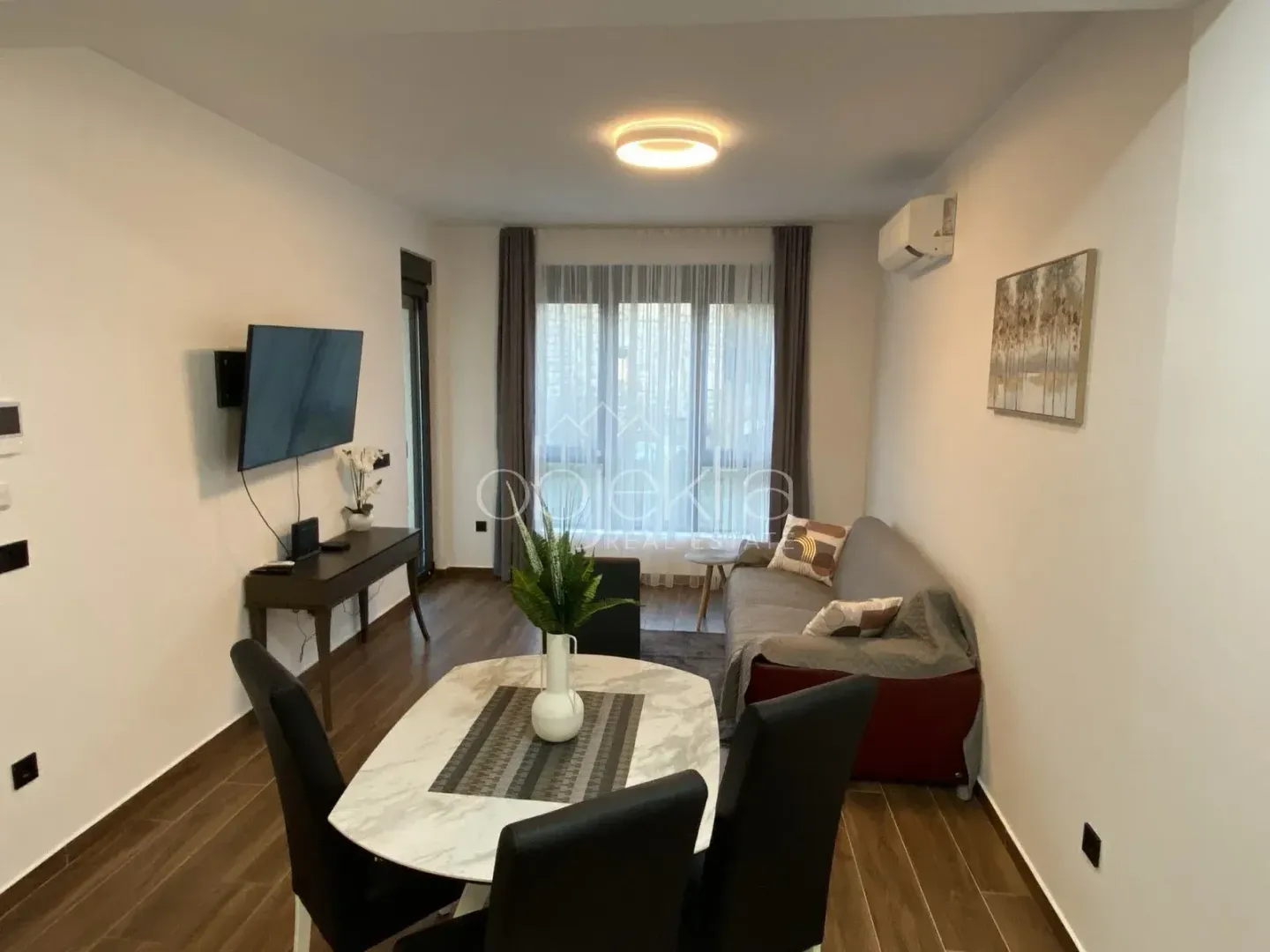 Dnevna soba sa trpezarijskim dijelom, garniturom i televizorom.