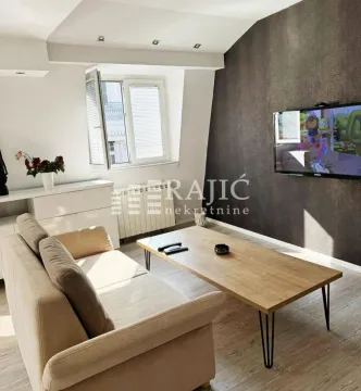Living room with a sofa, coffee table and wall-mounted TV. - image 2