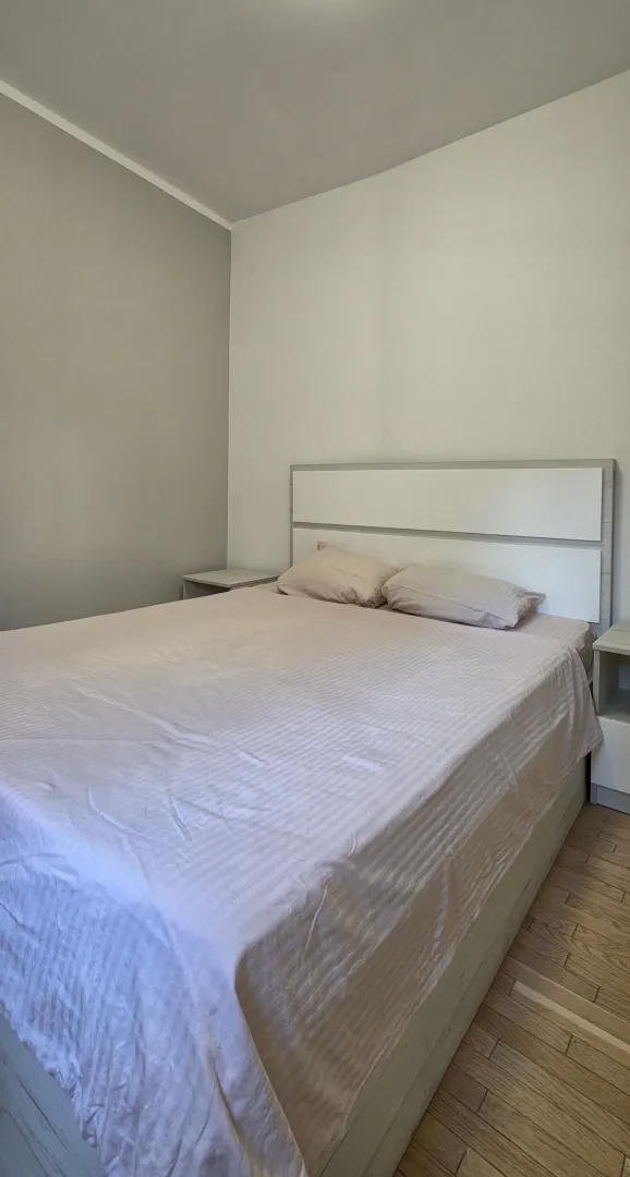 Svijetla spavaća soba sa bračnim krevetom i noćnim stočićima.