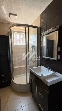 Kupatilo opremljeno tuš kabinom, umivaonikom sa ormarićem i ogledalom. - image 7